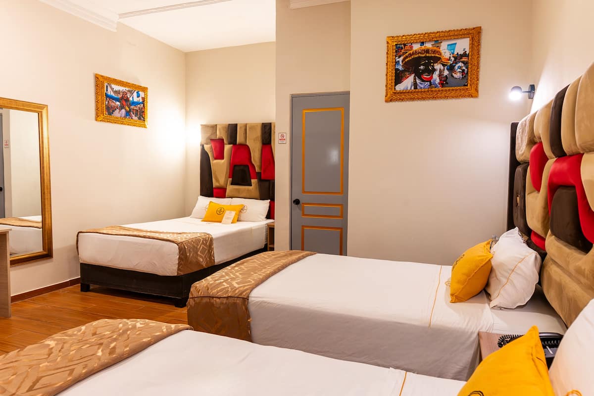A hotel room with two single beds, a large mirror, and a door with a red and beige curtain.