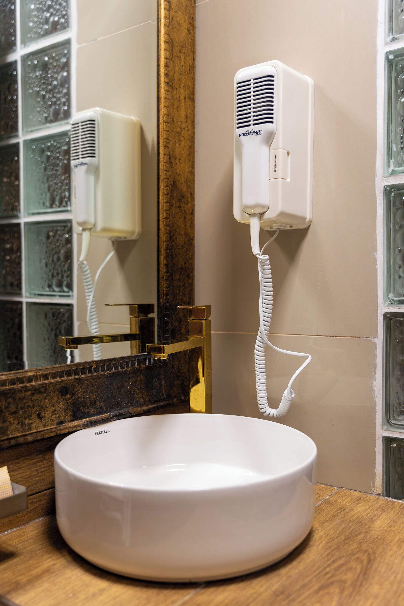 A bathroom with a white basin, a mirror, and a hairdryer mounted on the wall.