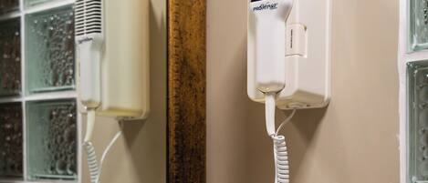 A bathroom with a white basin, a mirror, and a hairdryer mounted on the wall.