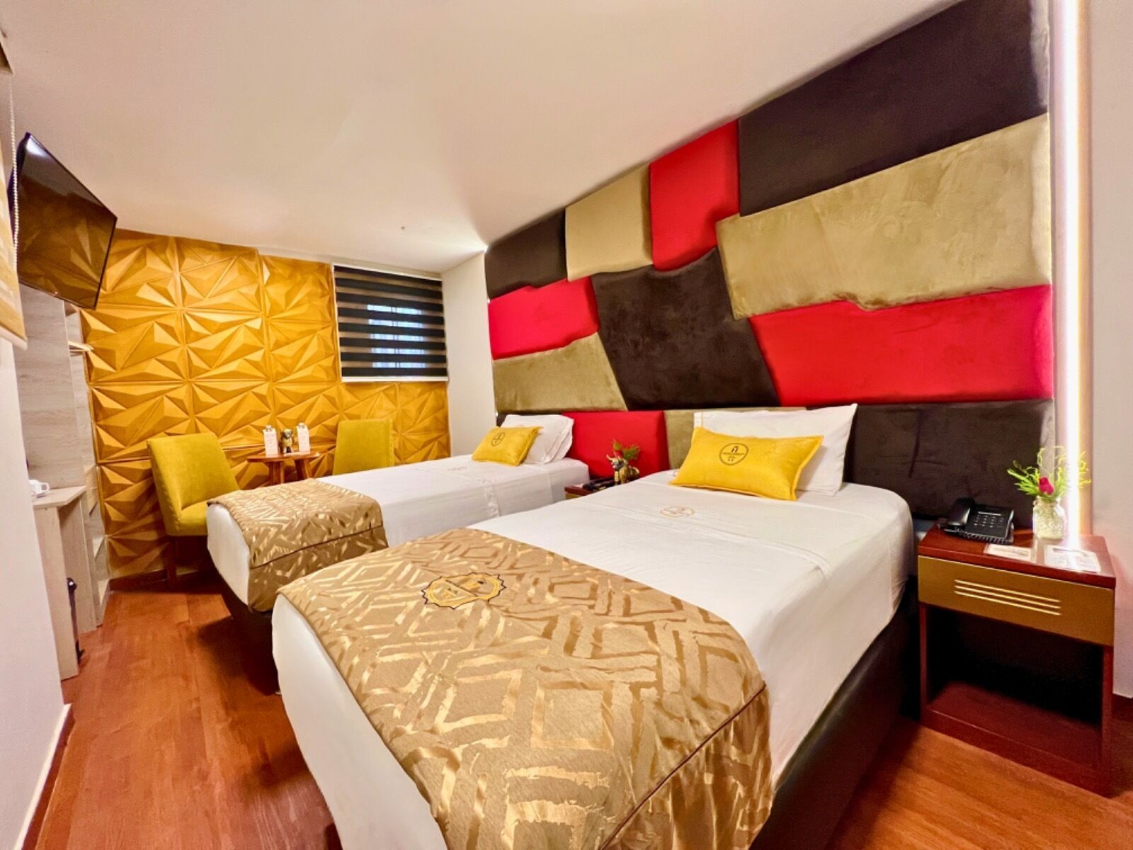 A hotel room with two beds, a small seating area, and a decorative wall.