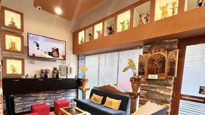 A modern living room with a sofa, red ottomans, a coffee table, and a TV mounted on the wall. - MONTREAL MAGDALENA HOTEL  (Lima)