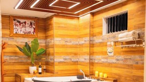 A modern bathroom with a freestanding bathtub, wooden flooring, a wall-mounted picture, and a small plant. - MONTREAL MAGDALENA HOTEL  (Lima)