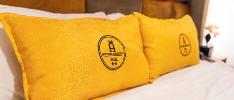 A bed with white bedding and two pillows with a logo and text.