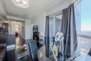 A modern living room with a glass dining table, a sofa, and a TV. - Stunning City Center 2 Bedroom 2 Bathroom Suite, Balcony, 3 TVs, Pet Friendly (Toronto)