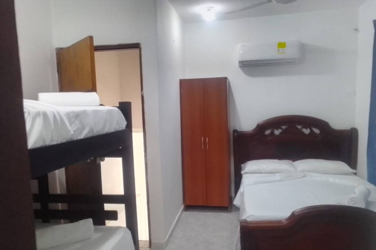 Una habitación de hotel pequeña y sencilla con literas, un armario y un equipo de aire acondicionado.