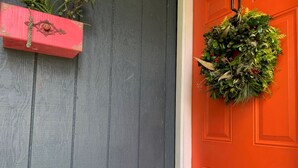 A gray door with a red door panel and a hanging wreath. - Puolani Iki-Sweet lil cottage near National Park (Volcano)