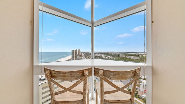 Vue d’un coin de balcon offrant une vue dégagée sur l’océan et le paysage urbain.