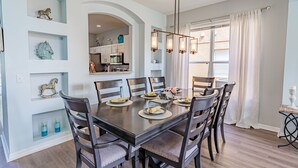 A dining area with a dark wooden table, six chairs, and a chandelier.