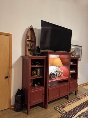 Ein Holz-Unterhaltungsschrank mit Fernseher, Regalen für Dekoration und einer Lampe.