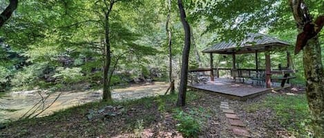 A forested area with a wooden gazebo and a stone pathway.