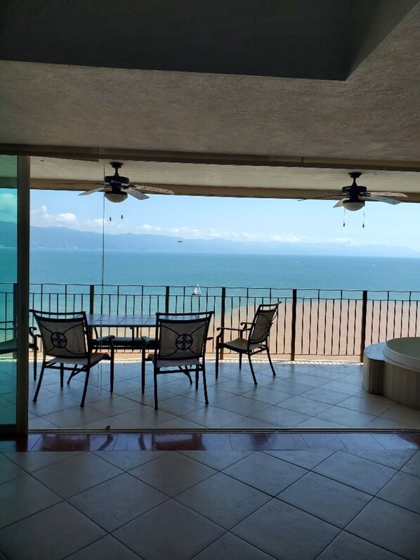 Ein Balkon mit Tisch und Stühlen mit Blick auf Strand und Meer.