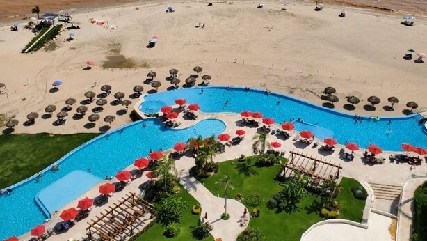 A resort with a large pool area, beach, and ocean view.