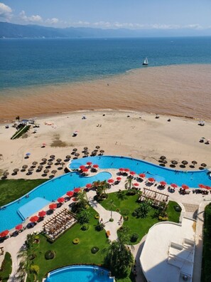 Ein Resort mit großzügiger Poolanlage, Strand und Meerblick.