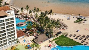 A resort with a large pool, beach, and mountain views.