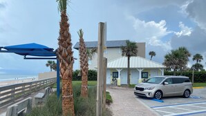 Un hotel fronte spiaggia con parcheggio, palme e vista sull'oceano.