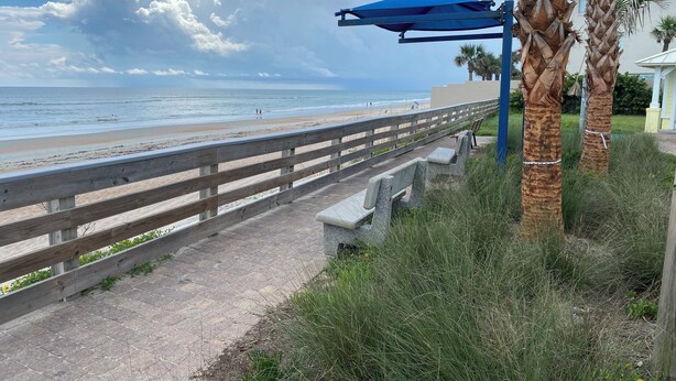 Una passerella di legno che conduce a una spiaggia con una struttura a tetto blu.