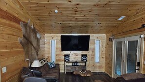 Ein gemütliches Cabin-Interieur mit Holzausstattung, Ledersitzgelegenheiten, einem Flachbildfernseher und einem großen Fenster.