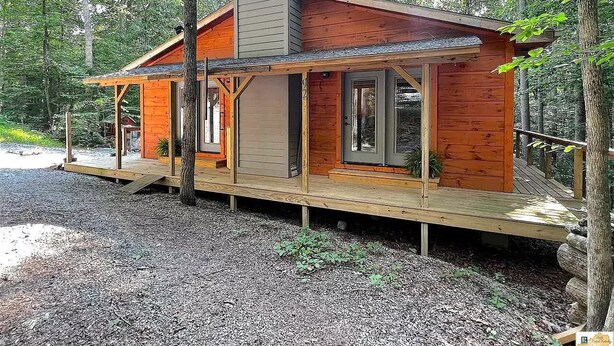 Eine Holzhütte mit einer Terrasse, umgeben von Bäumen.