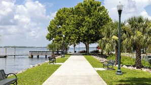 A waterfront walkway with benches, a lamp post, and a large tree. - New Home 3/2 With Garage Near Downtown (Mount Dora)