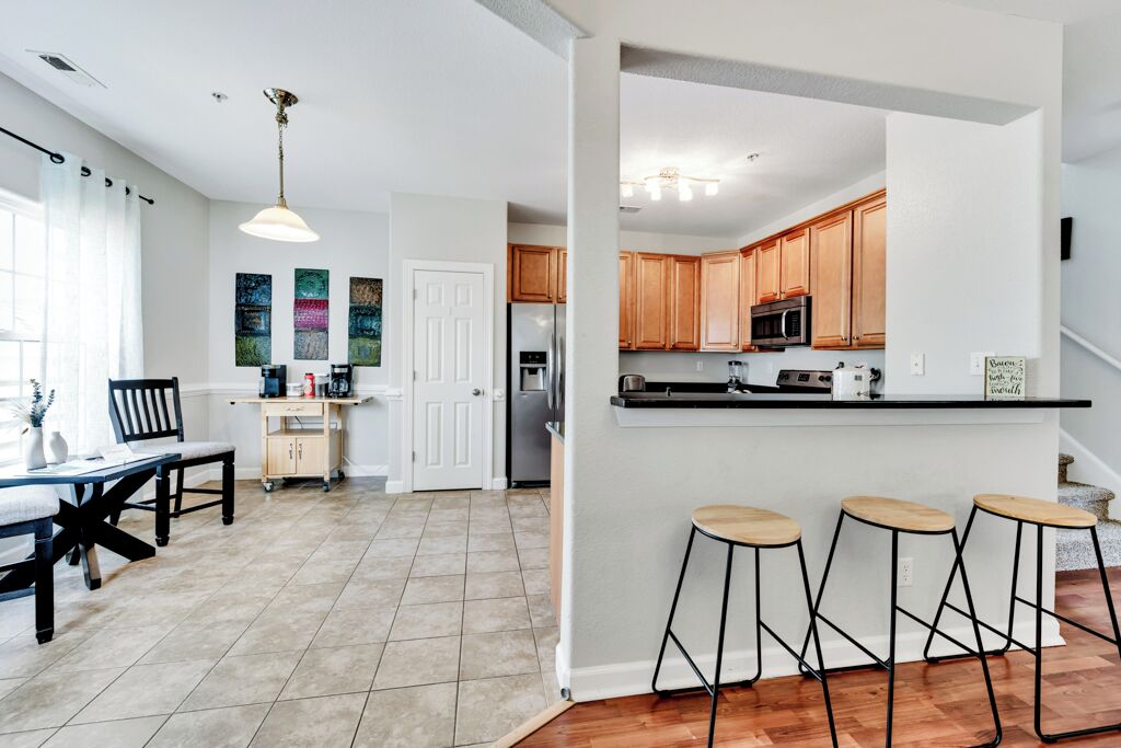 A modern kitchen with wooden cabinets, a black countertop, and a built-in island with stools.