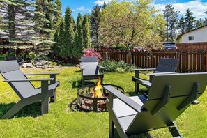 A backyard with a fire pit, outdoor furniture, and a wooden fence.