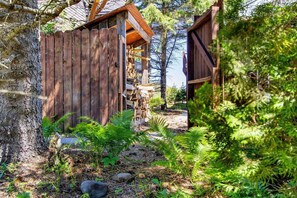 A rustic wooden structure with a wooden deck, surrounded by dense greenery and trees. - Beach Retreat on Park Point | Hot Tub • Fire Pit • Beach Access (Duluth)