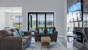 A modern living room with two sofas, a coffee table, and a TV mounted on a marble wall. - Pool overlooking canal, Outdoor Grilling station - Villa Sand Dollar Siesta (Cape Coral)