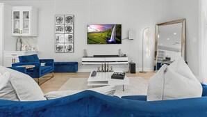 Un salon moderne comprenant une grande télévision, un canapé, une table basse et un meuble.