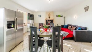 Una cocina moderna con refrigerador empotrado, mesa de comedor con sillas y un sofá rojo en la sala.