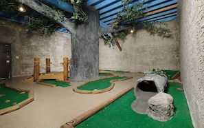 Un espace de jeux intérieur comprenant un arbre, une structure d’escalade et un tunnel.