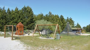 A playground with a wooden slide, swings, and a climbing net structure. - 4 bedroom stunning home in Strandby (Strandby)