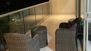 A balcony with wicker furniture and a glass railing. - Hermoso Apartamento Frente a la Playa (Cartagena de Indias)