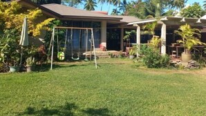 A house with a covered porch, a swing set, and a lawn.