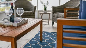 A covered patio area with wicker furniture, a wooden table, and a fan. - Waterfront Vacation Getaway (Hudson)