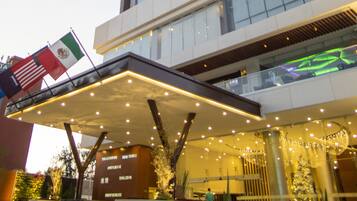 Un hotel de gran altura con diseño moderno, que presenta una entrada destacada con zona cubierta e iluminación decorativa.