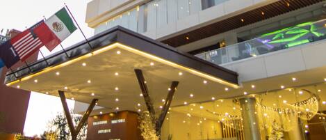 A high-rise hotel with a modern design, featuring a prominent entrance with a covered area and decorative lighting.