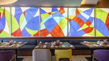 Un restaurante con un ventanal de vidrio emplumado de colores, múltiples zonas de estar y un interior moderno y limpio.