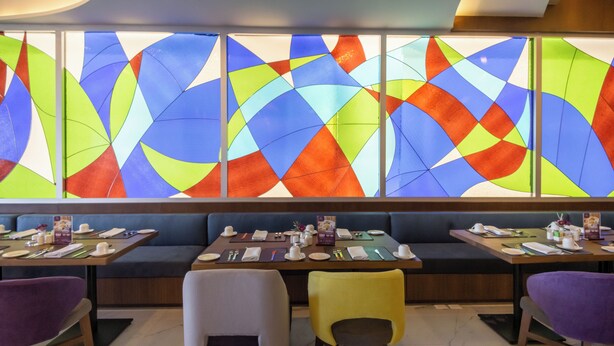 A restaurant with a colorful stained glass window, multiple seating areas, and a clean, modern interior. - Sheraton Guadalajara Expo (Zapopan)