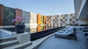 Un espace piscine extérieur moderne, avec des marches menant à un coin salon équipé de chaises longues.