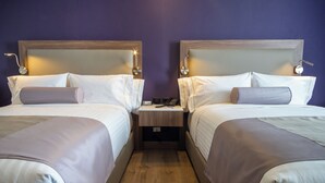 A hotel room with two beds, wooden headboards, bedside tables, and a nightstand with a phone. - Sheraton Guadalajara Expo (Zapopan)