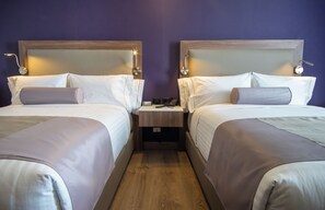 A hotel room with two beds, wooden headboards, bedside tables, and a nightstand with a phone. - Sheraton Guadalajara Expo (Zapopan)