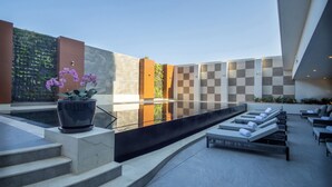 A modern outdoor pool area with steps leading to a seating area with lounge chairs. - Sheraton Guadalajara Expo (Zapopan)