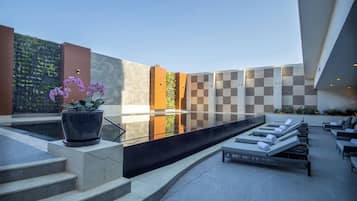 Un área de piscina moderna al aire libre con escalones que conducen a un espacio de descanso con sillones.