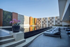 A modern outdoor pool area with steps leading to a seating area with lounge chairs. - Sheraton Guadalajara Expo (Zapopan)