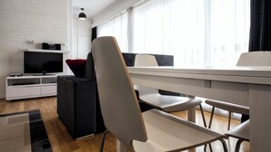 Una sala de estar moderna con un televisor de pantalla plana, una mesa de comedor con sillas y un sofá.