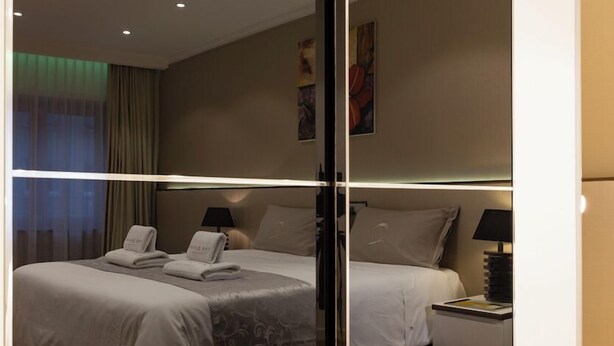 Une chambre d’hôtel avec deux lits, chacun équipé d’un oreiller et d’une serviette, une table de chevet avec une lampe et un mur décoré d’œuvres d’art.