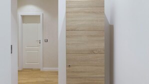 Un couloir avec une armoire en bois, une porte blanche et un plancher en bois.