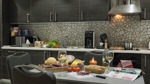 Une cuisine moderne avec des meubles de couleur sombre, un pare-feu en pierre et un coin repas avec une table mise pour le repas.