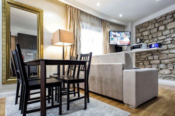 Un salon moderne comprenant un coin repas, un mur en pierre, un téléviseur à écran plat et un canapé.