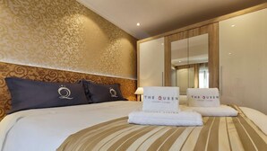 A hotel room with a large bed, two pillows with the hotel's logo, a bedside table with a lamp, and a mirror on the wall. - Liberty -52 Apartment, 1 Bedroom, Terrace (Luxembourg)